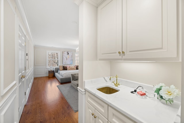 bar with dark wood-style floors, crown molding, a decorative wall, and a sink