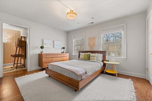 bedroom with visible vents, baseboards, and wood finished floors