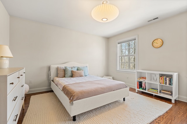 bedroom with wood finished floors, visible vents, and baseboards