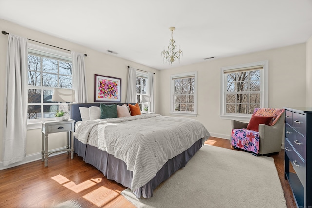 bedroom with visible vents, multiple windows, and wood finished floors