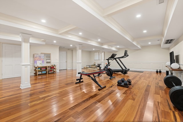 exercise room with visible vents, a decorative wall, wainscoting, light wood-type flooring, and ornate columns