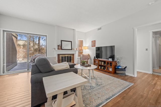 living room with light hardwood / wood-style flooring and a brick fireplace