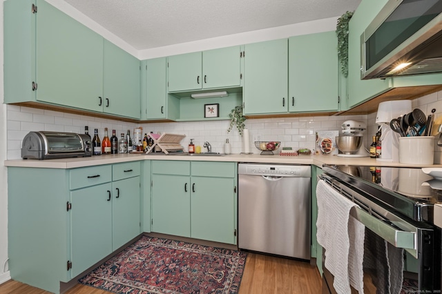 kitchen featuring light wood-type flooring, sink, tasteful backsplash, and stainless steel appliances