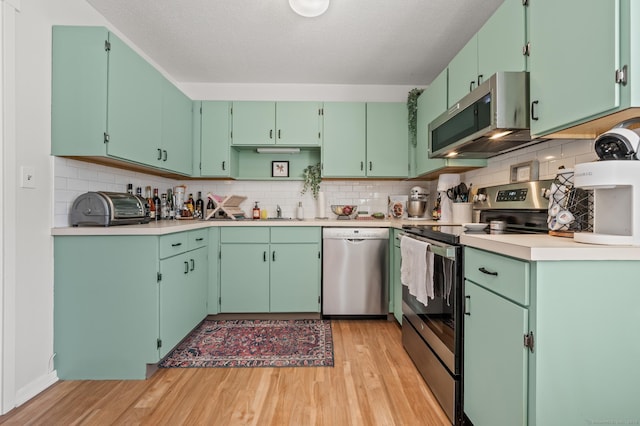 kitchen featuring backsplash, stainless steel appliances, and light hardwood / wood-style flooring