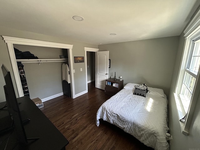 bedroom with dark wood finished floors, baseboards, and a closet