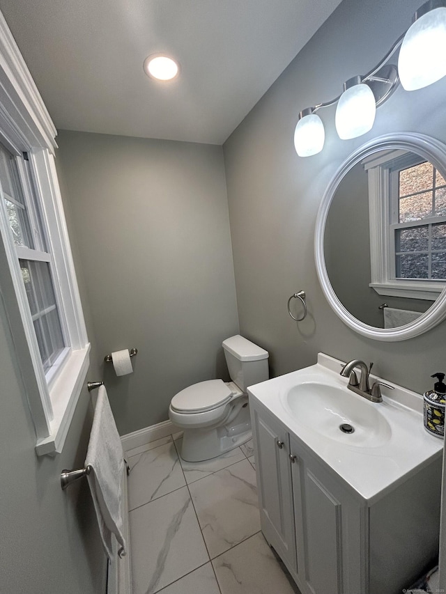 half bathroom with toilet, marble finish floor, recessed lighting, baseboards, and vanity