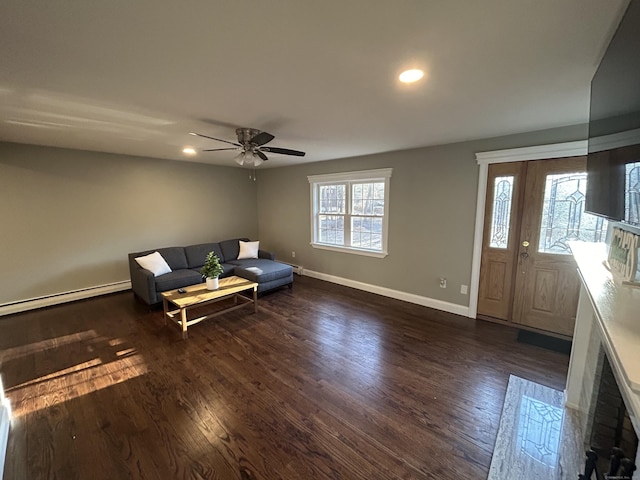 unfurnished living room with dark wood-style floors, plenty of natural light, a ceiling fan, and baseboards