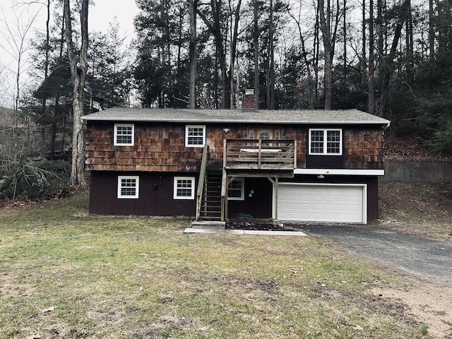 view of front of home with a front yard, stairway, an attached garage, a chimney, and aphalt driveway