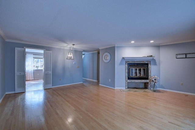 unfurnished living room featuring baseboards, a fireplace with flush hearth, ornamental molding, recessed lighting, and wood finished floors