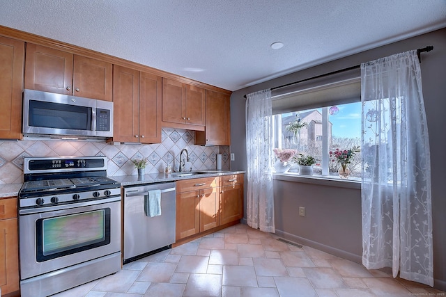 kitchen with a sink, decorative backsplash, appliances with stainless steel finishes, and brown cabinetry