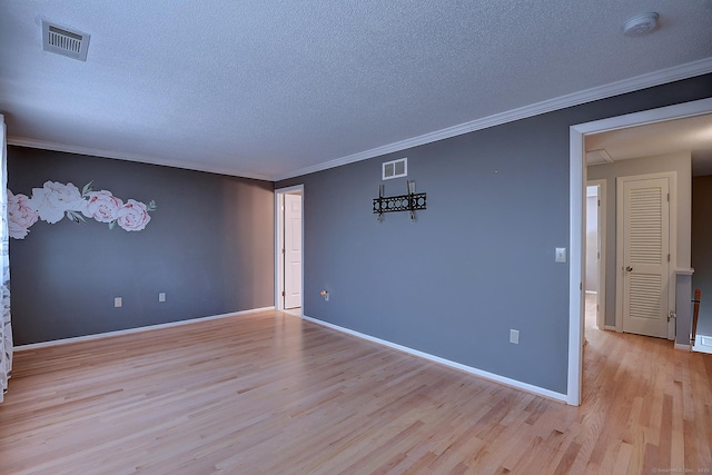 empty room with light wood-type flooring, visible vents, a textured ceiling, and crown molding