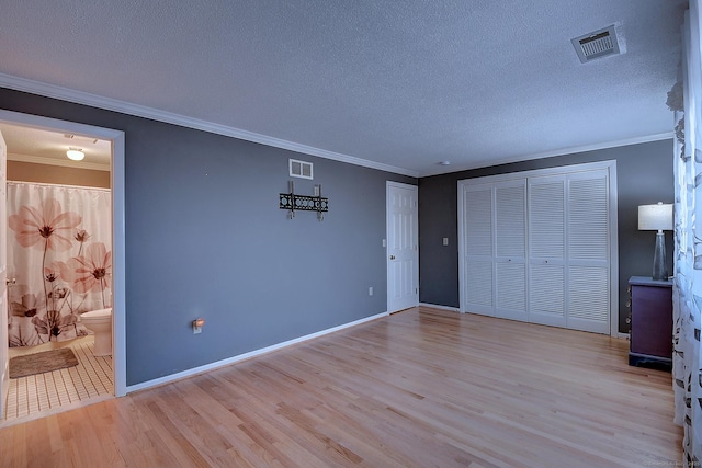 unfurnished bedroom with ornamental molding, light wood-style floors, visible vents, and a textured ceiling