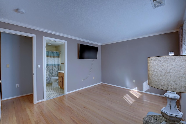 unfurnished bedroom with baseboards, visible vents, a textured ceiling, crown molding, and light wood-type flooring