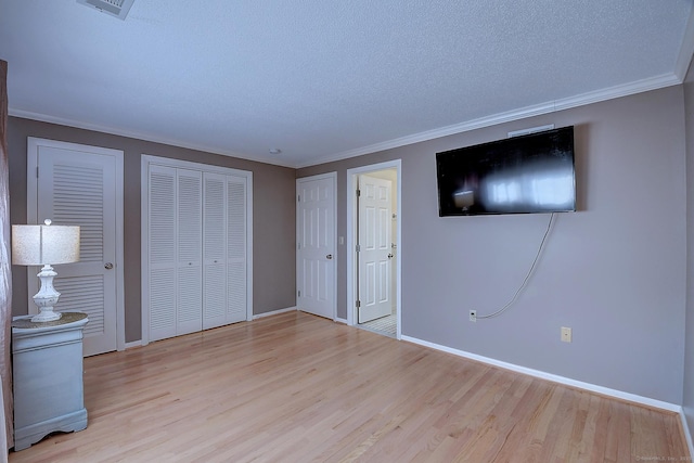 unfurnished bedroom featuring wood finished floors, baseboards, and ornamental molding