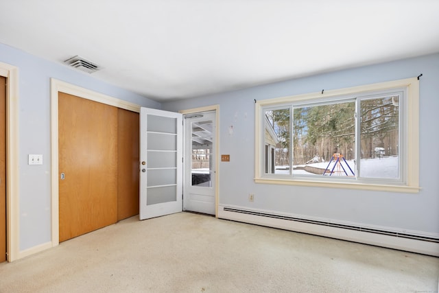 spare room with light carpet and a baseboard heating unit