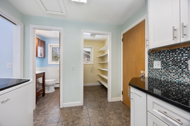 interior space with white cabinetry, decorative backsplash, tile patterned flooring, a baseboard heating unit, and range