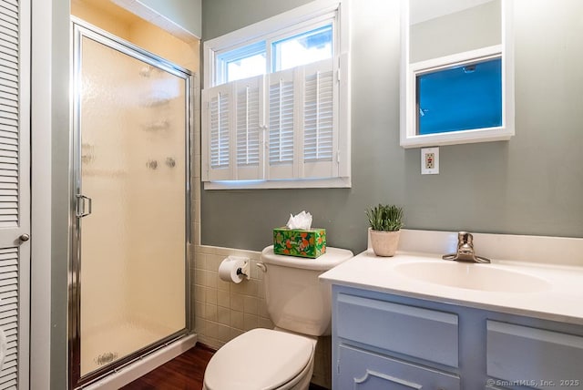 bathroom featuring vanity, toilet, a shower with shower door, and tile walls