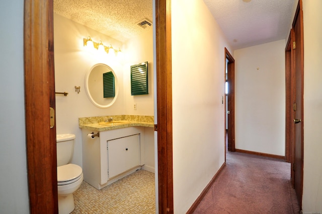 bathroom featuring vanity, a textured ceiling, and toilet