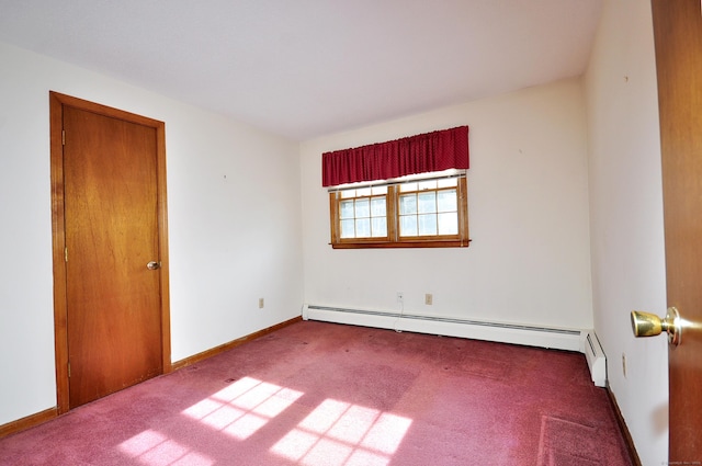 carpeted empty room featuring a baseboard heating unit