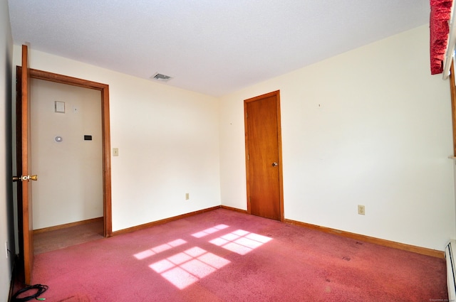 empty room with a baseboard heating unit and carpet flooring