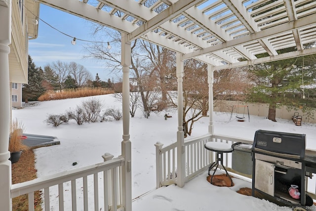 snow covered deck with area for grilling and a pergola