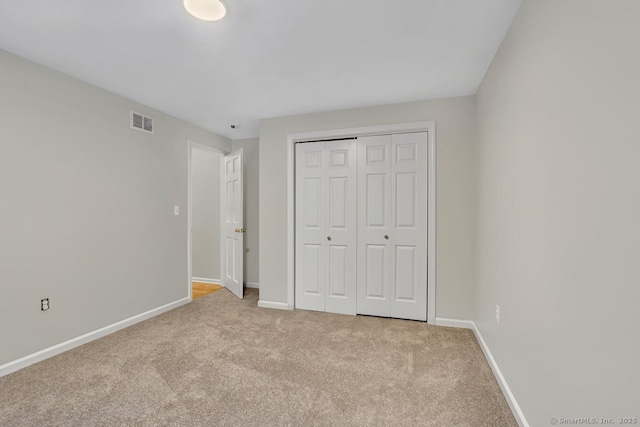 unfurnished bedroom with a closet and light carpet