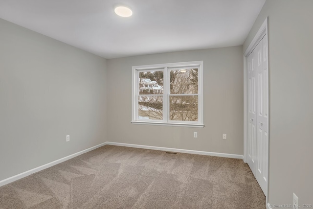 unfurnished bedroom with carpet, a closet, baseboards, and visible vents