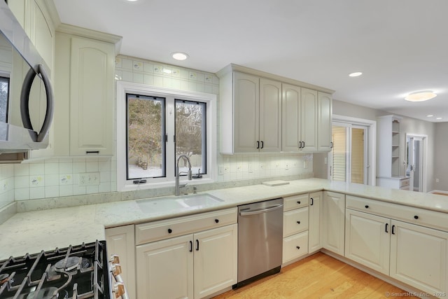 kitchen with decorative backsplash, light stone counters, stainless steel appliances, and a sink