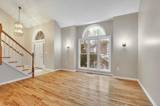 foyer with baseboards, visible vents, a chandelier, wood finished floors, and stairs