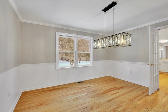 unfurnished dining area featuring visible vents, a wainscoted wall, wood finished floors, and crown molding