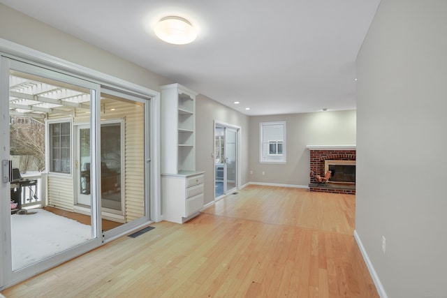 unfurnished living room with recessed lighting, visible vents, light wood-type flooring, baseboards, and a brick fireplace