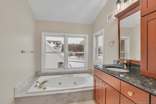 bathroom with lofted ceiling, visible vents, a whirlpool tub, and vanity