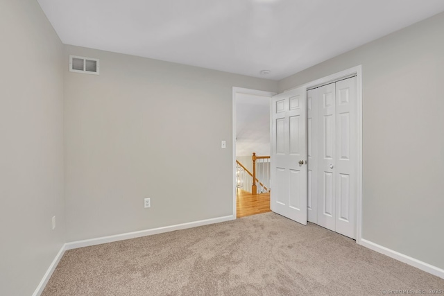 unfurnished bedroom featuring baseboards, visible vents, carpet floors, and a closet