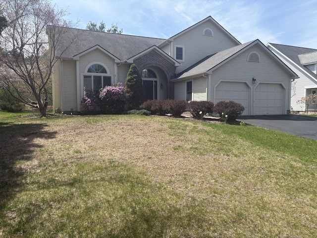 single story home with driveway, a front yard, a shingled roof, and a garage