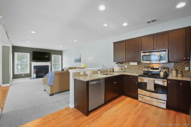 kitchen featuring light stone countertops, appliances with stainless steel finishes, sink, and backsplash