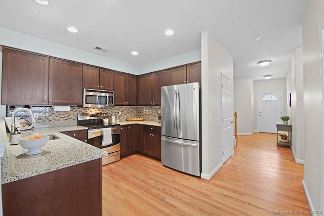 kitchen with light stone counters, dark brown cabinetry, appliances with stainless steel finishes, and decorative backsplash