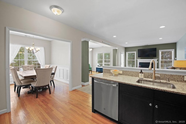 kitchen with plenty of natural light, dishwasher, sink, and light stone countertops