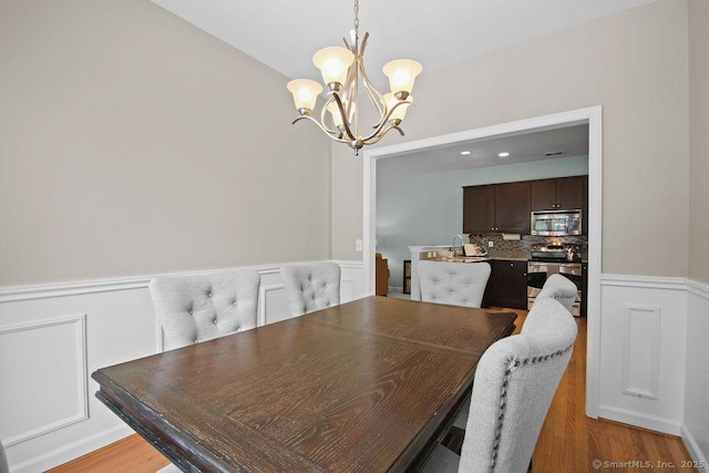 dining room with hardwood / wood-style floors and a chandelier