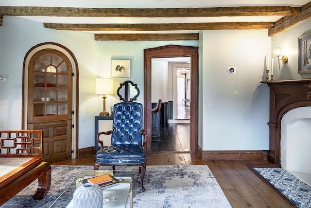 sitting room with beamed ceiling and dark wood-type flooring