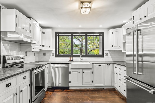 kitchen with sink, dark wood-type flooring, appliances with stainless steel finishes, white cabinetry, and tasteful backsplash