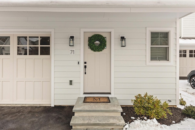 snow covered property entrance with a garage