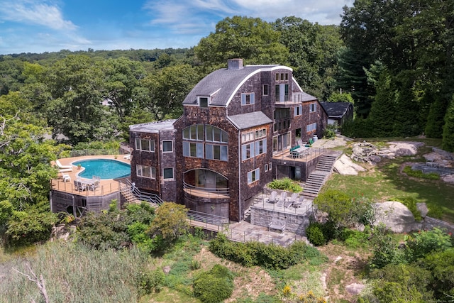 48 Andrews Rd, Guilford, CT 06437 - rear view of house featuring stairs, a wooded view, a community pool, a chimney, and a wooden deck