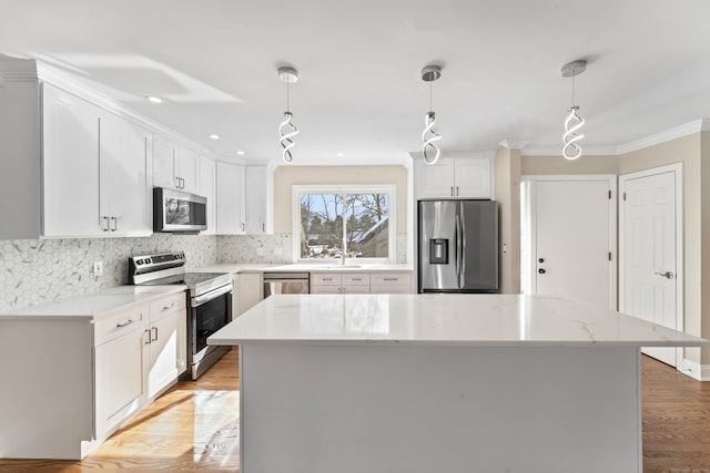 kitchen with crown molding, tasteful backsplash, stainless steel appliances, decorative light fixtures, and white cabinetry