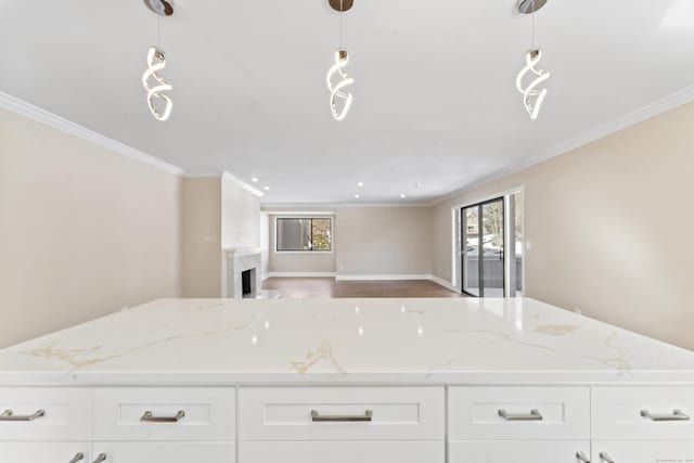 kitchen with ornamental molding, open floor plan, light stone countertops, and white cabinetry