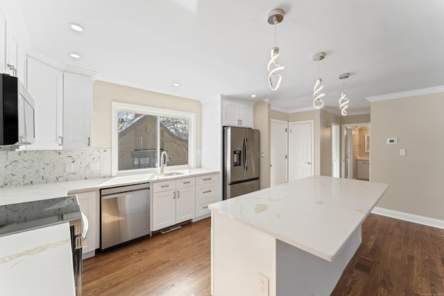 kitchen with white cabinets, a center island, a sink, appliances with stainless steel finishes, and ornamental molding