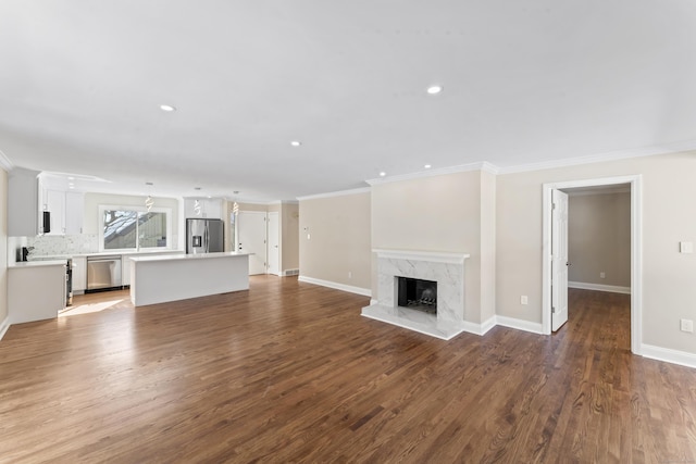 unfurnished living room with a premium fireplace, wood finished floors, crown molding, and baseboards