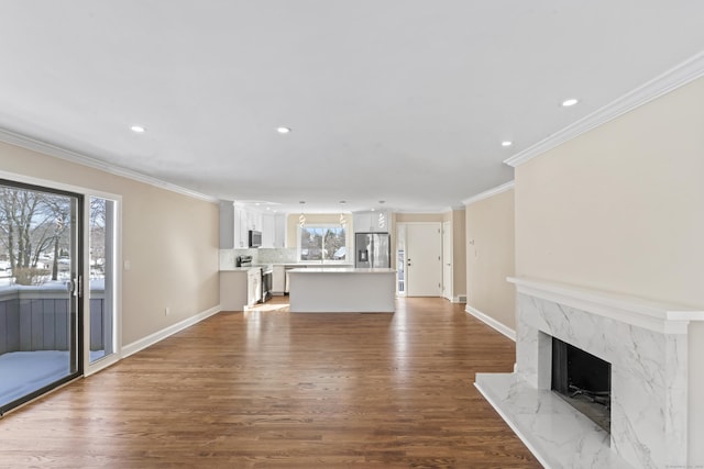 unfurnished living room featuring recessed lighting, a high end fireplace, wood finished floors, ornamental molding, and baseboards
