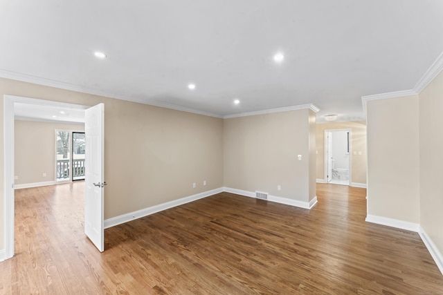 spare room featuring wood finished floors, visible vents, crown molding, and baseboards