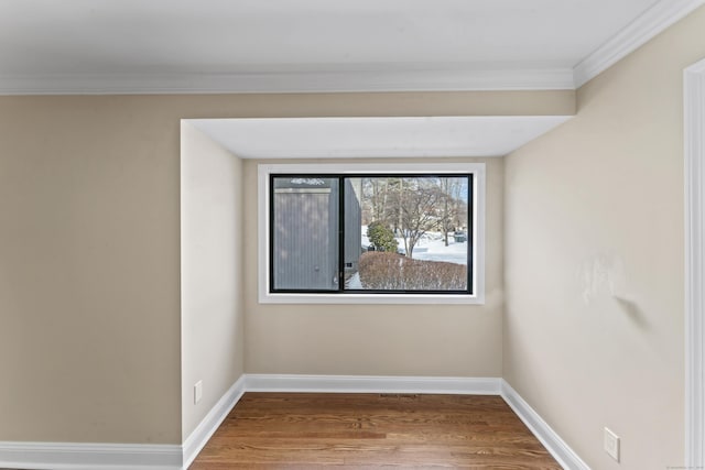 spare room featuring baseboards, wood finished floors, and ornamental molding