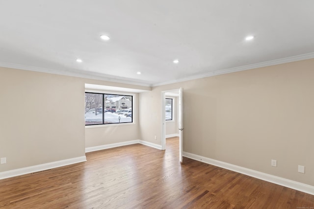 spare room with baseboards, crown molding, wood finished floors, and recessed lighting